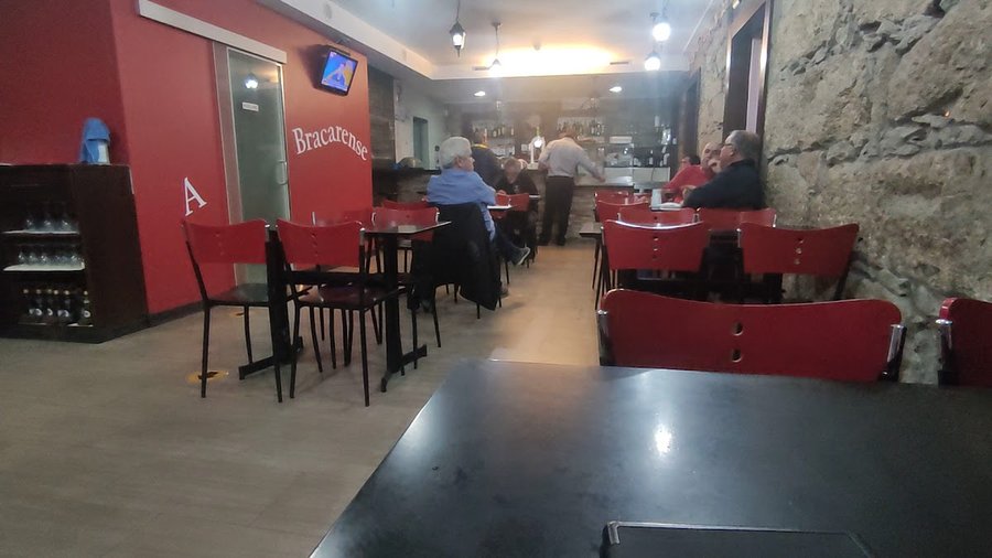 Interior da A Bracarense, com paredes de pedra e decoração vermelha