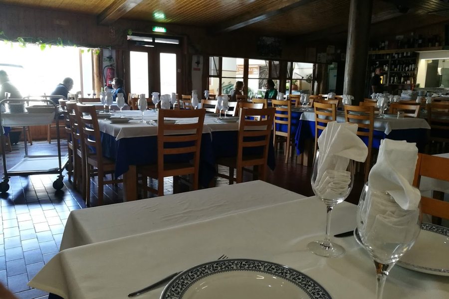 Sala de jantar do restaurante A Telha, em Vila Nova da Telha, com mesas de toalhas brancas e caminhos de mesa azuis, cadeiras de madeira e ambiente rústico