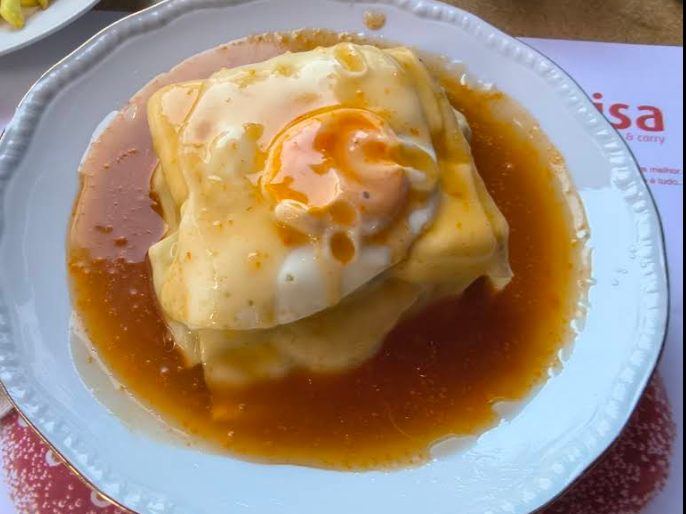 Francesinha com ovo estrelado e molho, servida no Bar do Clube Académico, em Pedras Rubras