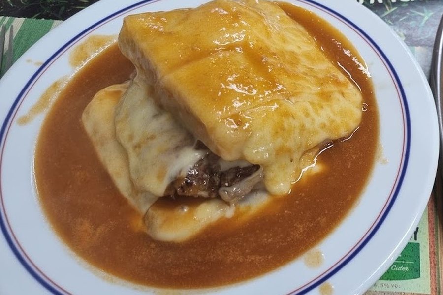 Francesinha do Café Raly coberta de molho e queijo derretido