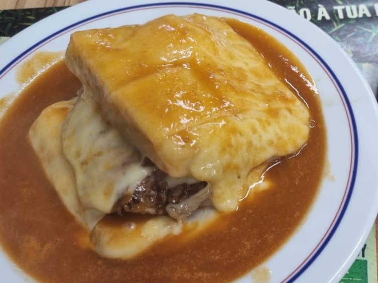 Francesinha ao prato, coberta de molho e queijo derretido, servida no Café Raly, em Pedras Rubras