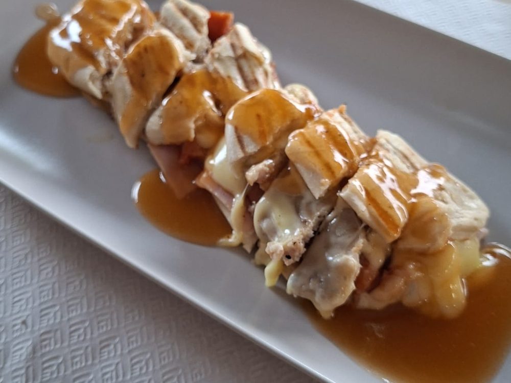 Cachorro Caldeirão com queijo e molho, cortado em fatias, no Caldeirão do Nelo