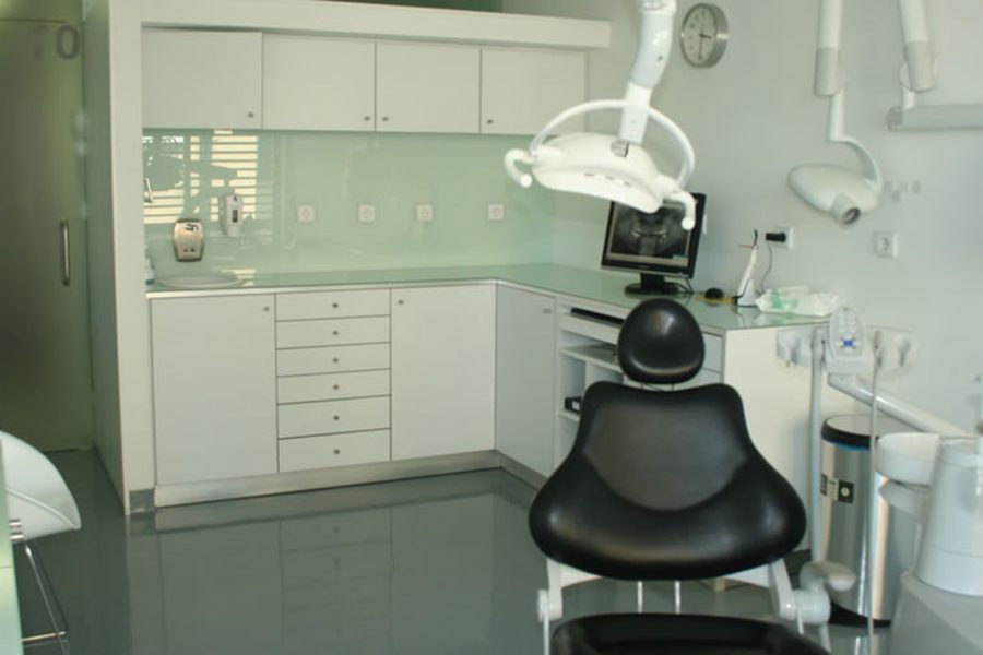 Outra sala de tratamento da Clínica Médica Dentária Vitor Borges, com cadeira, monitor e armários brancos