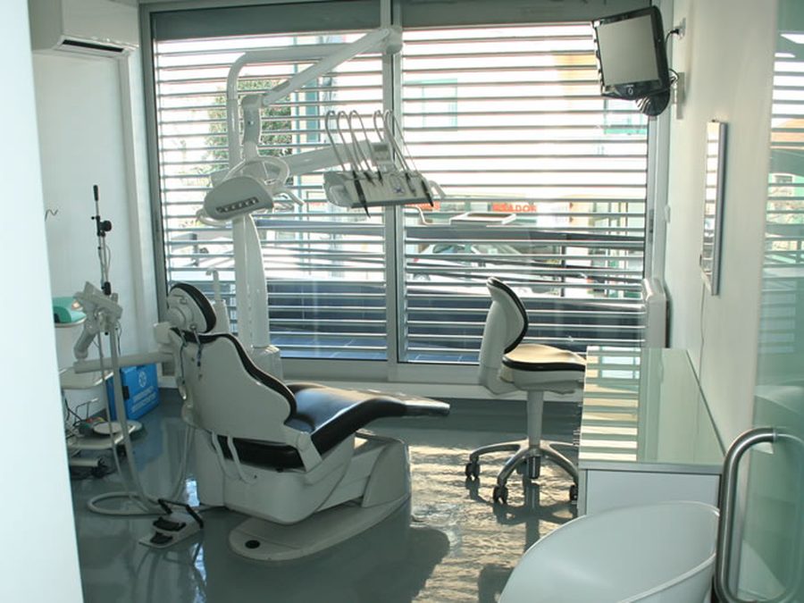 Sala de tratamento da Clínica Médica Dentária Vitor Borges, com cadeira e equipamento junto a uma janela ampla