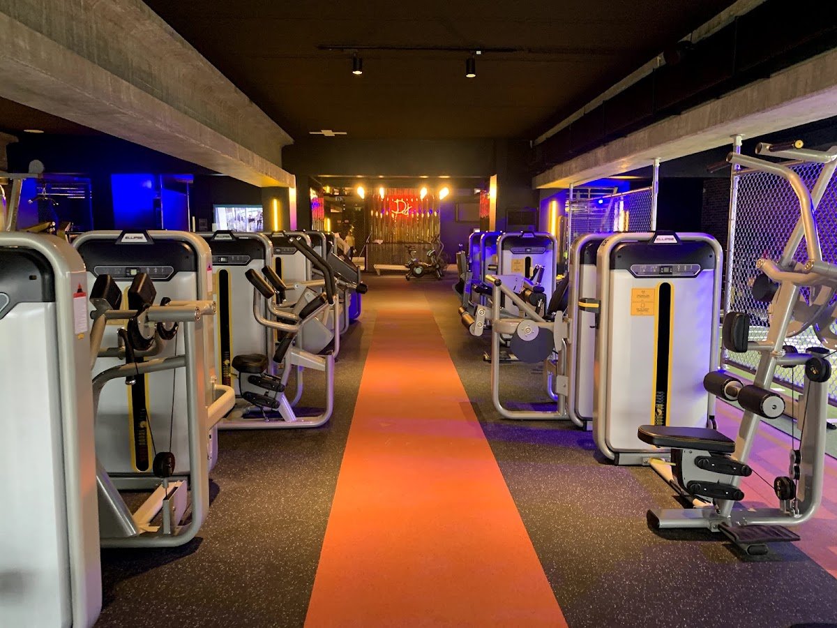 Sala de máquinas de força do Fitness UP, na Maia, com corredor laranja ao centro