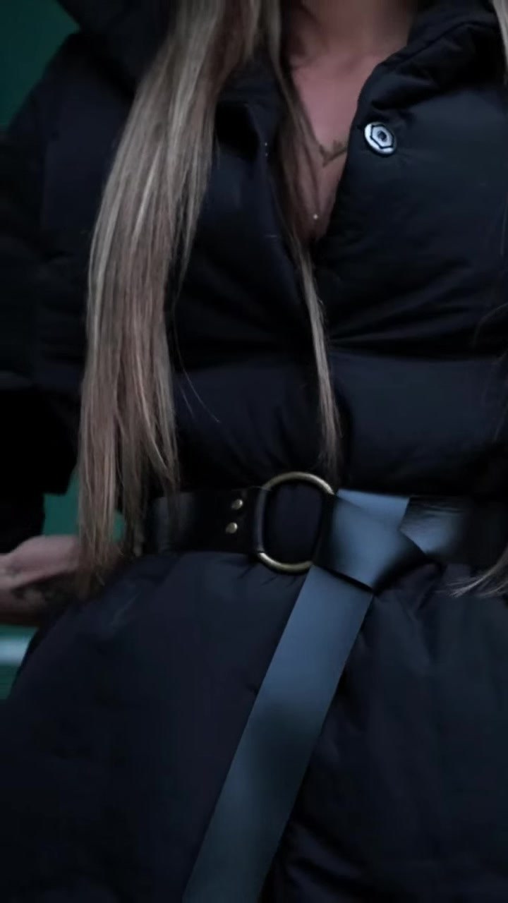 Pormenor do cinto de fivela dourada sobre o casaco preto, num look da Lady Space