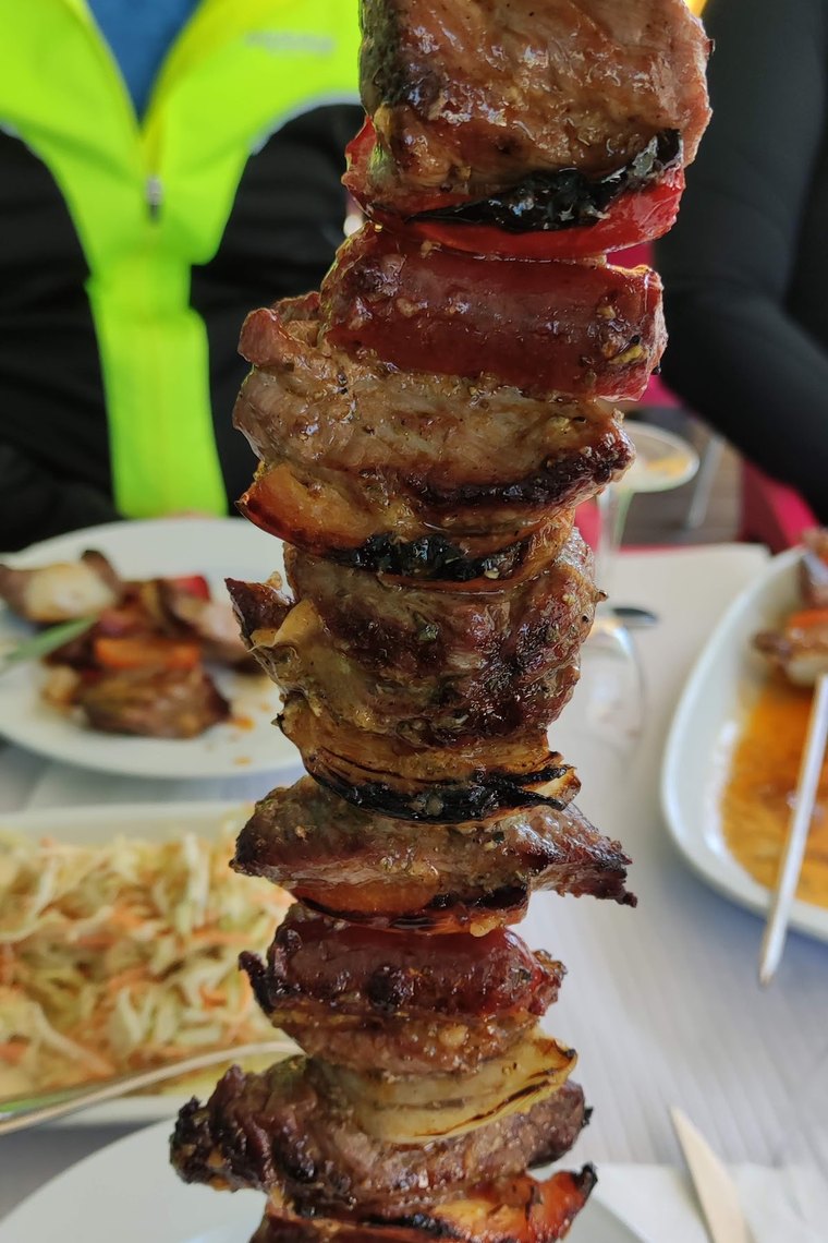 Espetada pendurada num gancho, com carne, chouriço, bacon e pimento, servida à mesa no Mira Metro