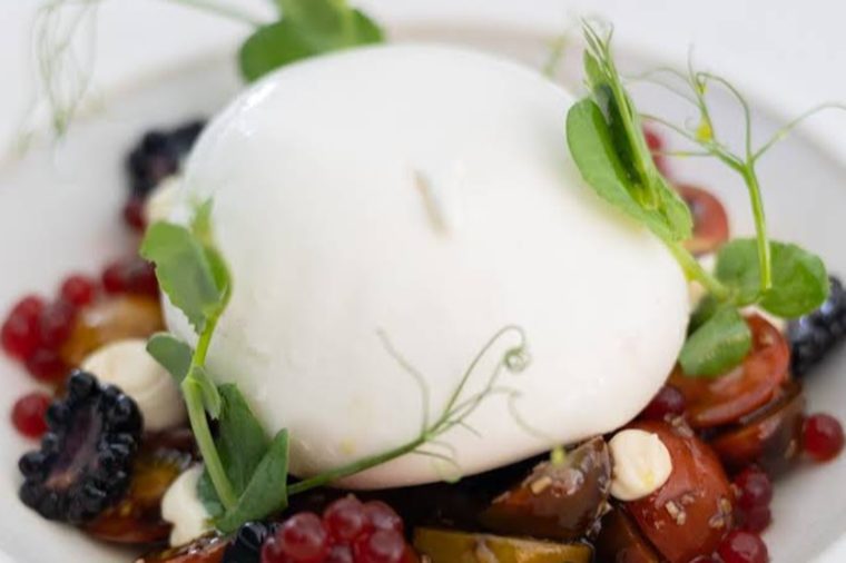 Burrata fresca com frutos vermelhos e rebentos, servida no Momenti D'Oro