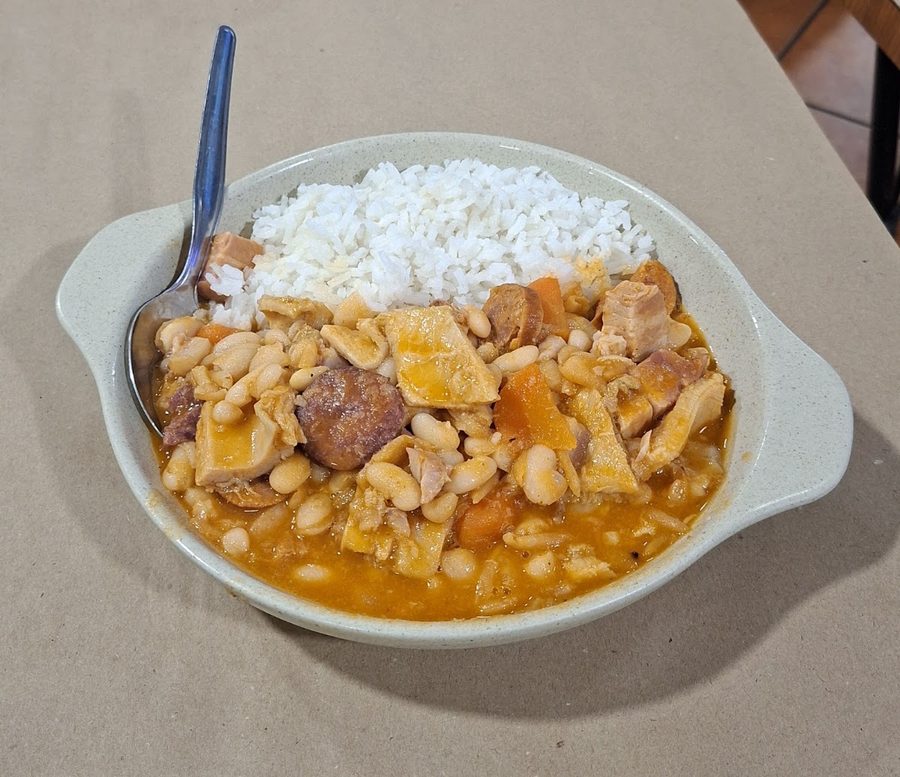 Feijoada de feijão branco com carnes e enchidos, servida com arroz branco numa travessa de barro, no restaurante O Banquinho