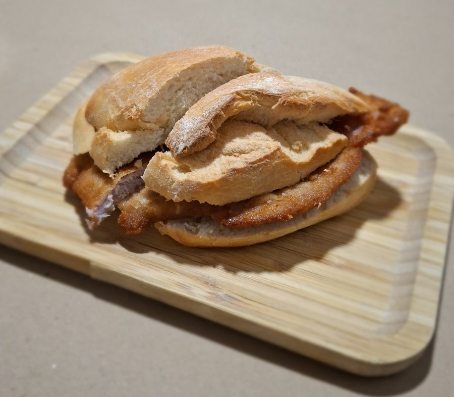 Sandes de panado em pão, servida numa tábua de madeira, no restaurante O Banquinho