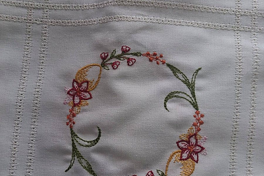 Bordado floral à mão sobre pano branco, trabalho d'O Baú Retrosaria