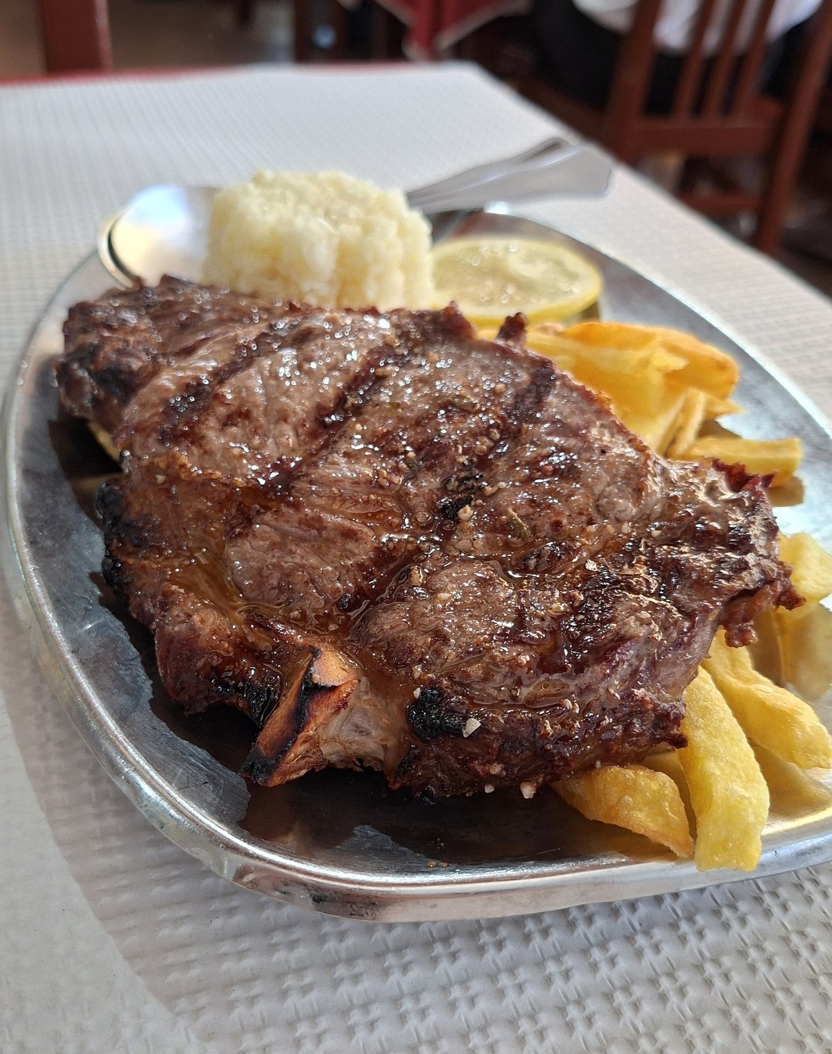 Costeleta de vitela grelhada com batata frita, arroz e limão, na travessa do Restaurante O Convite