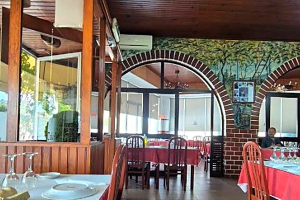 Sala do Restaurante O Convite, com teto de madeira, arcos de tijolo e toalhas vermelhas