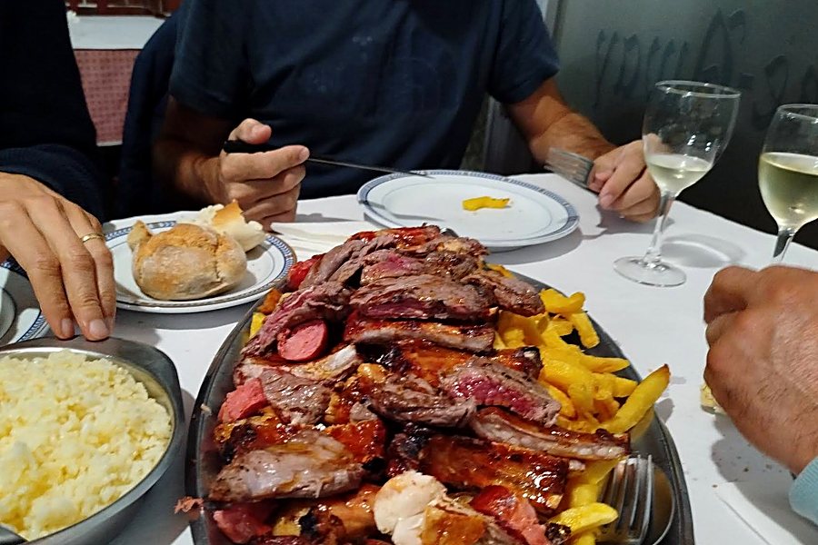 Travessa de churrasco misto com arroz, batata frita e pão, na mesa do Restaurante O Convite em Pedras Rubras
