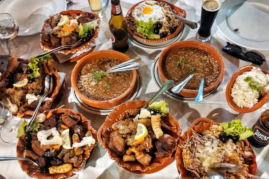 Mesa cheia de petiscos minhotos em tachos de barro, no restaurante O Forno, em Pedras Rubras