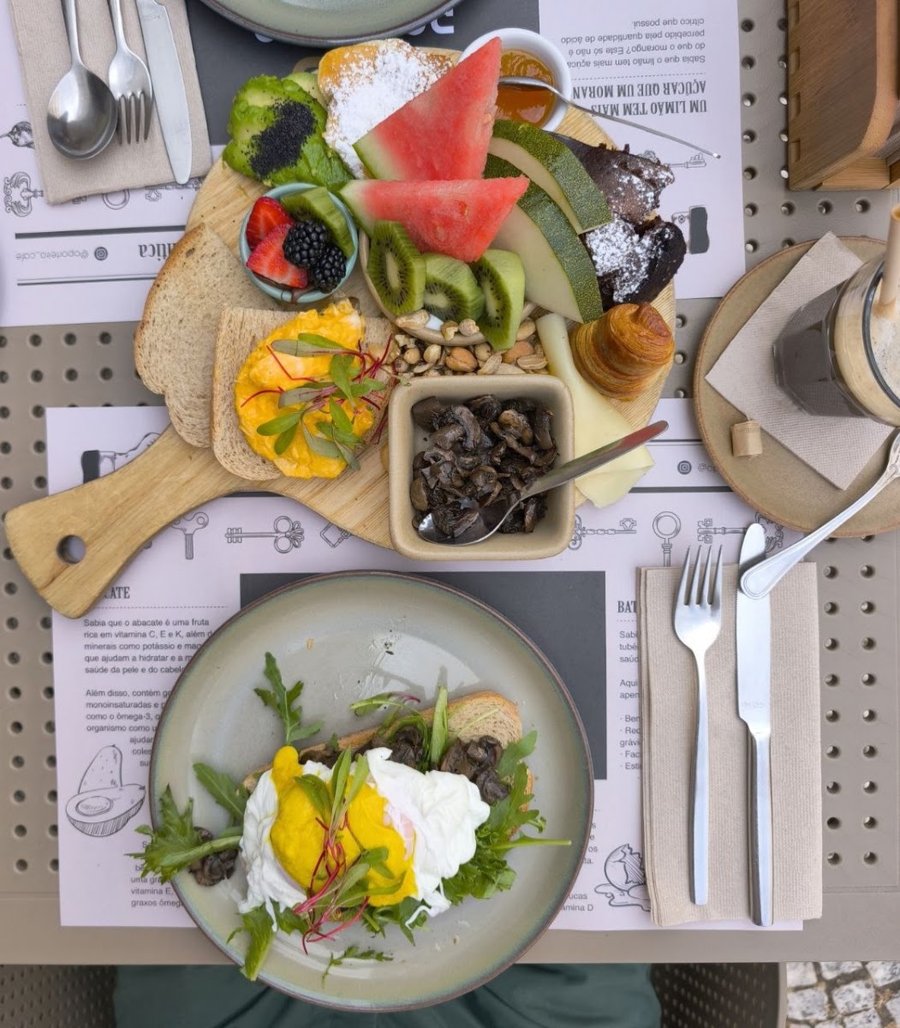 Tábua de brunch d'O Porteiro vista de cima, com melancia, kiwi, frutos vermelhos, granola e um prato de ovos escalfados