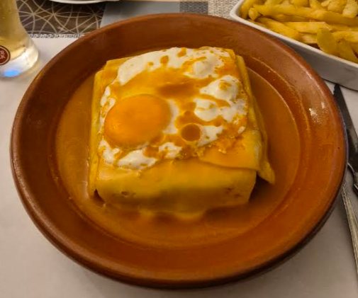 Francesinha com ovo a cavalo e molho, servida numa travessa de barro no Restaurante O Sapão