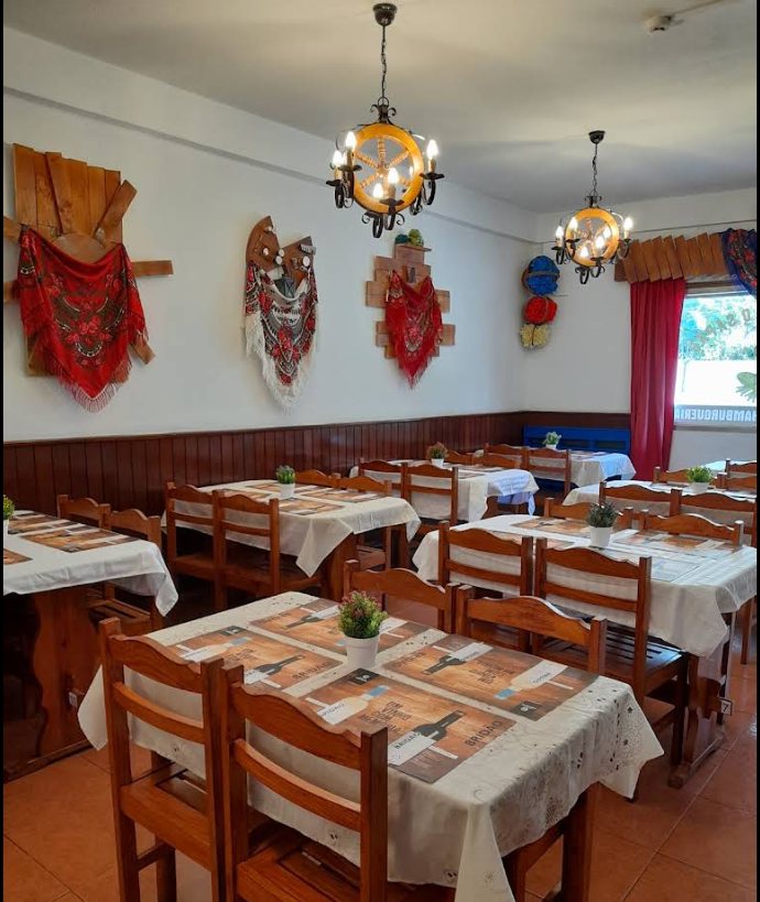 Sala do Restaurante O Sapão, com xailes de fadista pendurados na parede e mesas postas