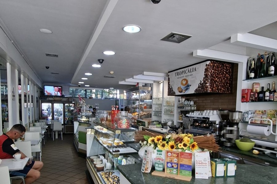 Salão da Pastelaria Tropicália em Pedras Rubras, com o balcão verde em curva, as vitrinas de bolos e as mesas do café