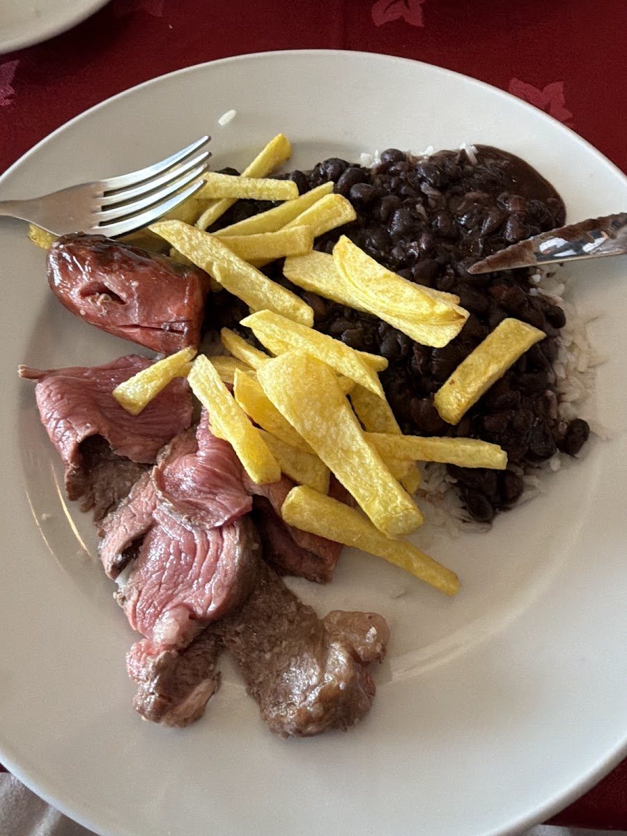 Prato com carne fatiada do rodízio e chouriço, batata frita, arroz e feijão preto