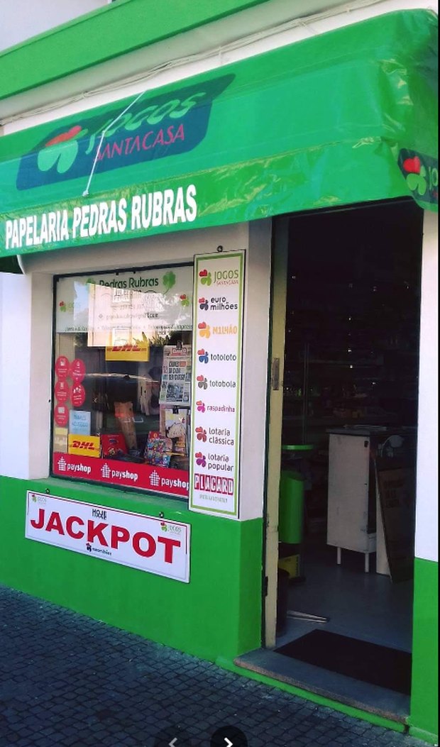Fachada da Tabacaria Pedras Rubras, com o letreiro verde Jogos Santa Casa e o painel Jackpot