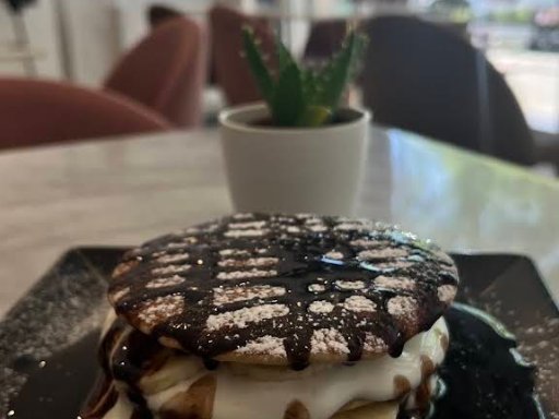 Panquecas com chocolate e natas numa mesa junto à janela do Velvet