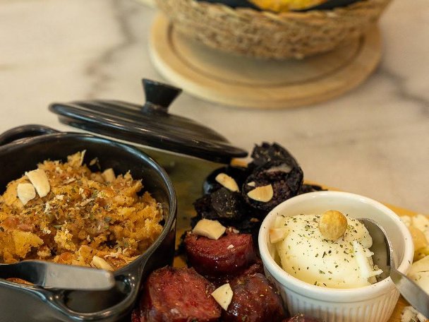 Tábua de petiscos do Velvet com chouriço assado, morcela, queijo e pão em cesto