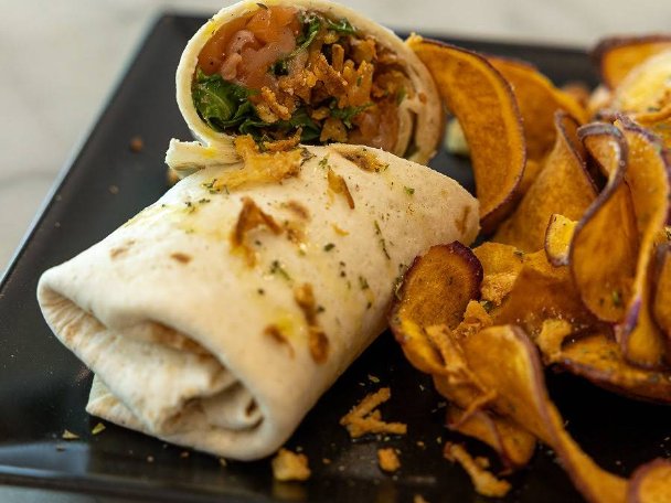 Wrap com chips de batata-doce servido em prato preto no Velvet