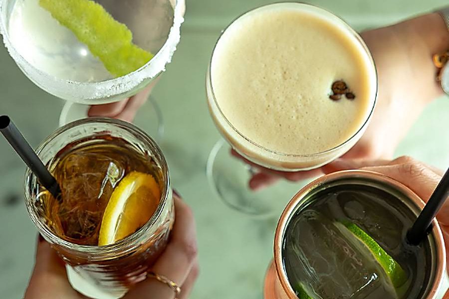 Quatro cocktails a brindar vistos de cima sobre uma mesa de mármore no Velvet, em Pedras Rubras