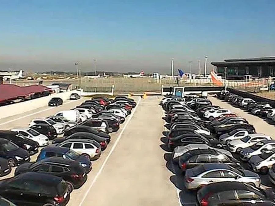 Row of cars parked in the open next to the Porto Airport terminal