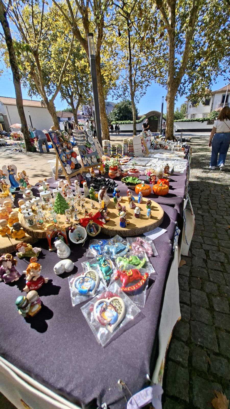 Mesa de banca de velharias com figuras de presépio e de Natal, pastores de barro e porcelana alinhados