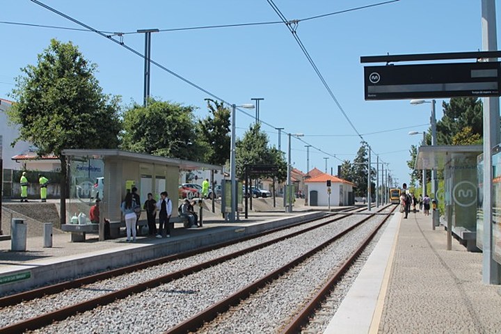 Plataforma da estação de Pedras Rubras, com o abrigo, pessoas à espera e a via da Linha B a perder-se ao longe