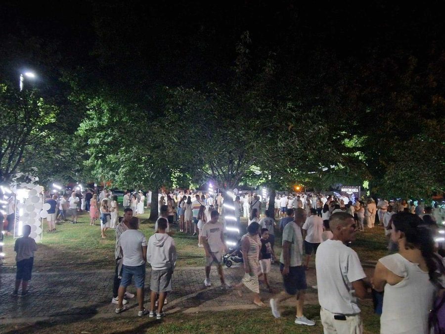 Multidão vestida de branco à noite, debaixo de árvores, numa edição anterior da Noite Branca no Parque de Quires