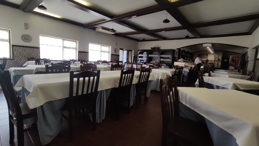 Sala de jantar do Pinheiral dos Leitões, com mesas de toalhas brancas, cadeiras de madeira e tecto de vigas de madeira