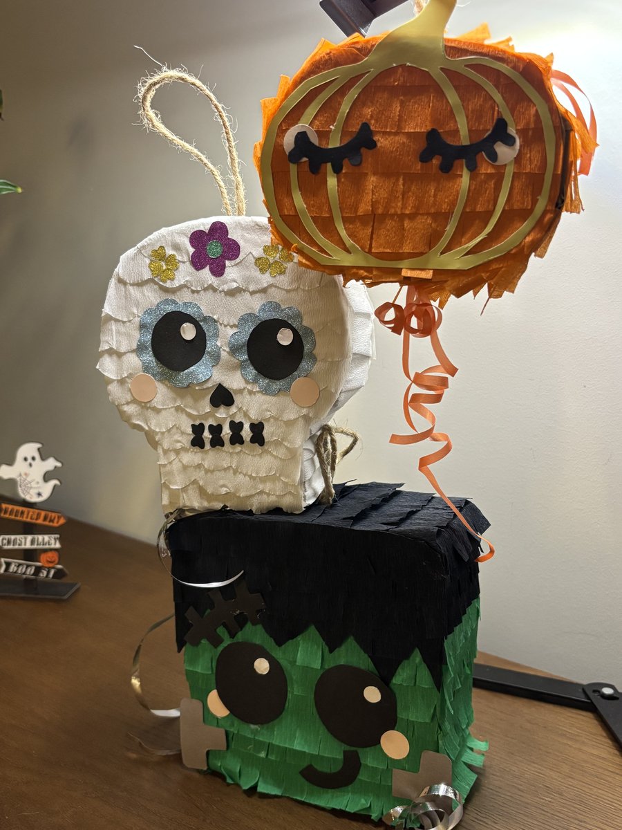 As três pinhatas de Halloween juntas em cima de uma mesa: caveira, abóbora e Frankenstein