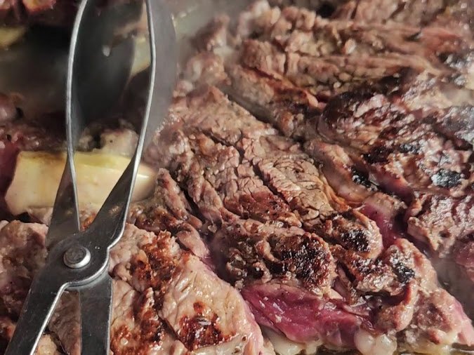 Carne grelhada fatiada com morcela, numa travessa com tenaz, no Tourigalo, na Maia